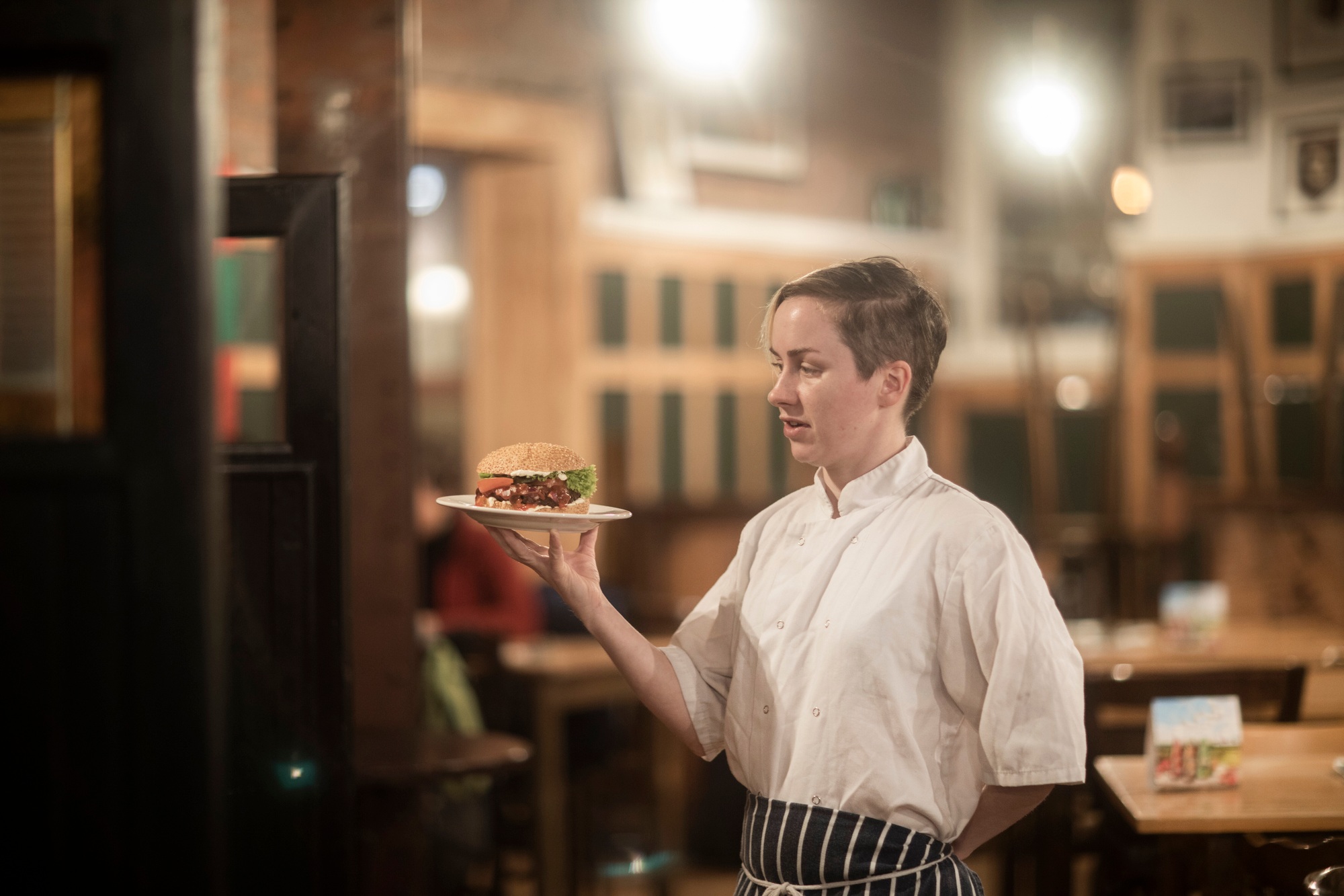 Waitress serving plate of burger in gastro pub